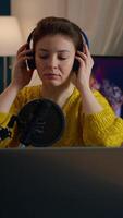 Vertical . Famous blogger streaming from home studio putting headphones recording vlog. On-air online production internet broadcast show host streaming live content record digital social media communication video