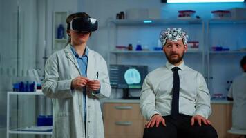 Advanced neurological scientist using medical inovation in lab wearing virtual reality glasses, gesticulating. Team of researchers working with equipment device, future, medicine, healthcare, vision, simulator video