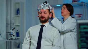 Neurologist doctor analysing brain of man and nervous system using brainwave scanning headset. Researcher using high tech developing neurological innovation monitoring side effects on monitor screen video