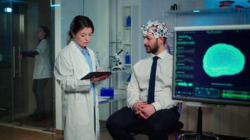 Specialist doctor in neuroscience taking notes on clipboard while testing brain functions of man using eeg headset, treating nervous system dysfunctions in moden laboratory. video