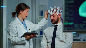 Expert research doctor in neuroscience developing treatment for neurological diseases discussing patient evolution using tablet. Doctor researcher analyzing brain functions and health status video