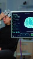 Vertical . Neurologist doctor analysing nervous system using eeg headset scanning woman brain. Scientist researcher using high tech developing neurological innovation, monitoring side effects on monitor screen video
