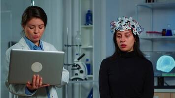 Expert medic in neuroscience developing brain experiment holding laptop explaning to woman side effects of nervous system treamtment. Team of scientists working in neurological research laboratory video