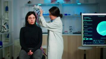 Medical lab technician adjusting eeg headset monitoring brain functions, descovering diagnosis of disease. Team of scientists researchers working late night in neurology clinic for woman health video