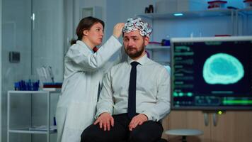 Patient with brain scan discussing with researcher neurological doctor while adjusting brainwave scanning headset examining diagnosis of disease, explaning eeg results, health status, brain functions video