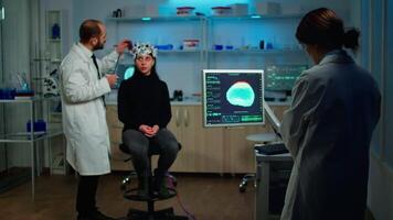Man doctor examining sensors of eeg headset, monitoring brain functions, while medical researcher analysing tomography scan on monitor, working in scientific neurological laboratory video