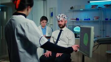 Man patient with high tech headset device participating at neurological experiment in technologically advanced laboratory testing physical reactions and nervous system video