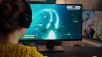 Back view of professional online gamer woman playing shooter game. Pro esport team player streamer playing gaming tournament on powerful RGB computer, using modern streaming technology video