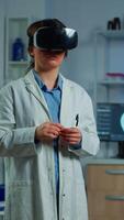 Vertical . Advanced neurological scientist using medical inovation in lab wearing virtual reality glasses, gesticulating. Team of researchers working with equipment device, future, medicine, healthcare, vision, simulator video