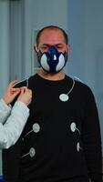 Vertical . Woman researcher preparing patient for endurance test using electrodes and professional body equipment. Team of doctors monitoring health of man with special mask, ekg scan runs on computer screen. video