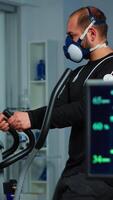 Vertical . Monitor showing EKG reading of athlete running on cross trainer, while medical specialists supervise exercise, controlling physical activity, measuring heart rate in sports science laboratory video