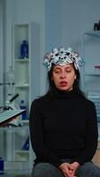 Vertical . Researcher neurologist doctor asking patient's symptoms taking notes on tablet, adjusting high tech eeg headset. Doctor researcher controlling EEG headset analyzing brain functions and health status video