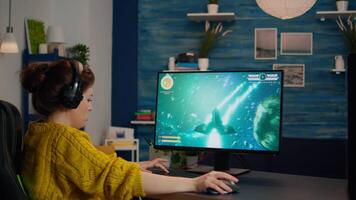 Expert woman gamer playing space shooter game on powerful PC. Virtual shooter game championship in cyberspace, esports player performing on computer in stylish room during gaming tournament video
