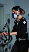 Vertical . Doctor witing on clipboard health informations while patient with mask running on cross trainer and man medical researcher monitoring vo2, physical enducance, heart rate and psychological resistance video