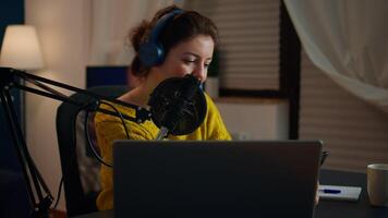 Happy blogger reading messages of fans using smartphone sitting in home podcast studio during livestreaming, recording. Online show On-air production internet broadcast host streaming live content video