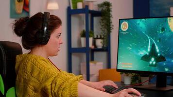 Focused professional woman player wearing headset playing space shooter game on powerful pc. Online streaming cyber performing on powerful personal computer during gaming tournament video