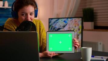 Blogger talking into microphone holding notepad with green screen during entertainment podcast. On-air production internet broadcast host streaming live content using chroma key, mockup display video