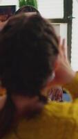 Vertical . Mixed race of people with sticky notes on foreheads playing name game having fun with beer and popcron keeping social distacing. with face mask to prevent spread of covid19 in home living room. video