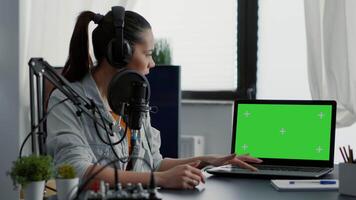 Influencer in studio presenting product on laptop with green screen background. Creative content creator recommending touchscreen device with chroma key with isolated display and mockup template video