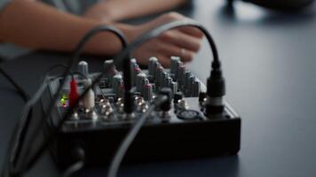 Woman tweaking audio mixer knobs and buttons. Internet radio host changing volumes and using studio sound console equalizer to improve broadcast audio quality. Close up shoot video