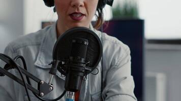 Internet live radio talk show host with headphones talking to audience at microphone in studio. Creative content creator sitting at desk while hosting podcast broadcast in living room. video