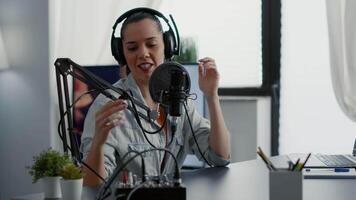Creative podcaster hosting internet live talk show while sitting in studio. Popular influencer discussing last news with audience while wearing headphones and using professional microphone. video