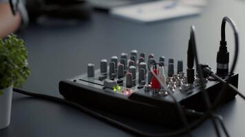 Influencer tweaking audio mixer knobs and buttons. Internet live talk show host changing volumes while using studio console equalizer to improve broadcast sound quality. Close up shoot video