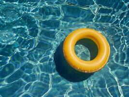 yellow inflatable ring floating at swimming pool. horizontal summer photo with copy space. background with water texture