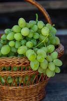 Bunch of white grapes in a basket on a wooden background. photo