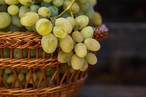 Bunch of white grapes in a basket on a wooden background. photo