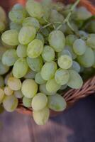 Bunch of white grapes in a basket on a wooden background. photo