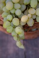 Bunch of white grapes in a basket on a wooden background. photo