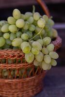 Bunch of white grapes in a basket on a wooden background. photo