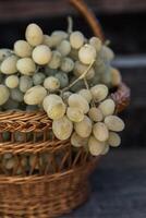 Bunch of white grapes in a basket on a wooden background. photo