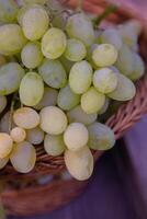 Bunch of white grapes in a basket on a wooden background. photo
