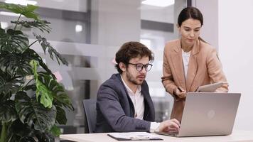 Two business people using a laptop together in a meeting. Happy business people looking at a slide presentation in an office. Presentation in boardroom with coworkers for corporate business seminar video