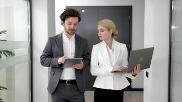 Two business people using a laptop together in a meeting. Happy business people looking at a slide presentation in an office. Presentation in boardroom with coworkers for corporate business seminar video