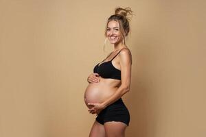 photo of pregnant woman standing pose with beige background,