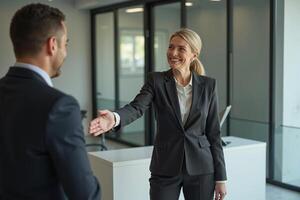 photo of woman in black blazer with open hand and colleagues in the office,