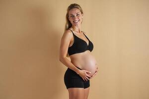 photo of pregnant woman standing pose with beige background,