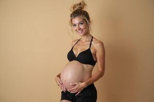 photo of pregnant woman standing pose with beige background,