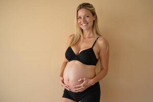 photo of pregnant woman standing pose with beige background,