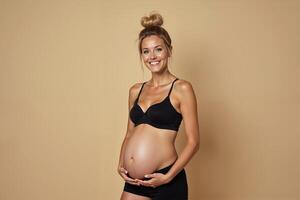 photo of pregnant woman standing pose with beige background,