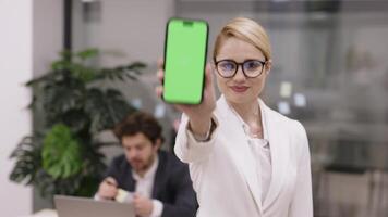 Close-up of a smartphone with a green screen in the hand of a female office worker against the business background. The ability to place information on the phone. video