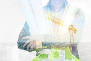Double exposure image of professional engineer in protective helmet and blueprints paper at building construction site photo