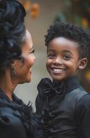 un joven negro chico felizmente vestido como un vampiro, sonriente con orgullo a su madre foto