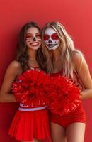 A cheerleader and her friend displaying red and white pompoms, wearing Halloween costumes with skull makeup photo