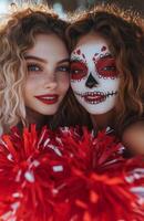 A cheerleader and her friend displaying red and white pompoms, wearing Halloween costumes with skull makeup photo