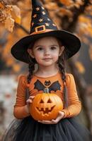 A young girl with black pigtails, an orange shirt, a witch hat, and a pumpkin photo