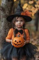 A young girl with black pigtails, an orange shirt, a witch hat, and a pumpkin photo